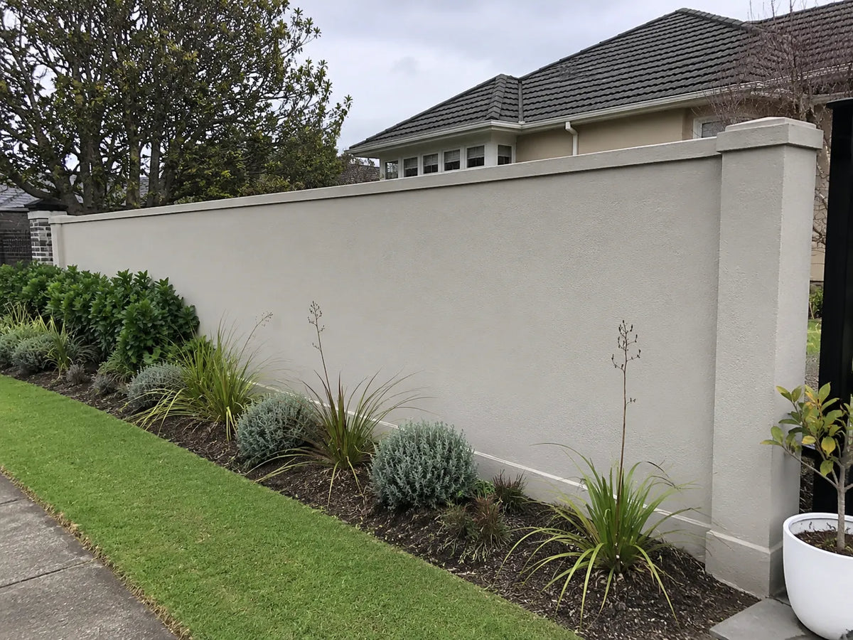 Lightly textured rendered garden wall beside simple Canterbury planting