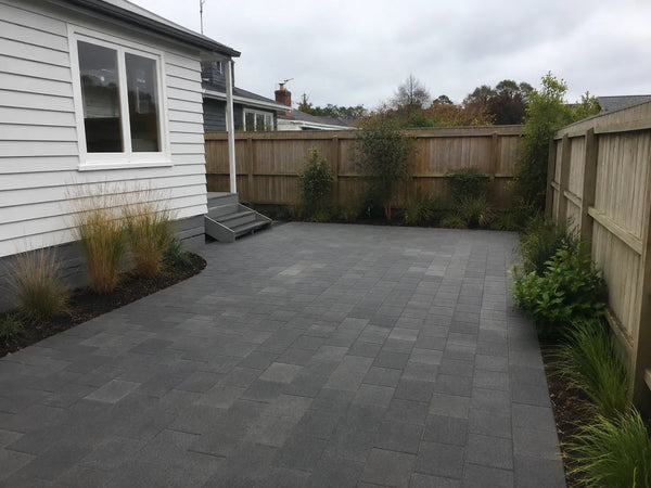 Completed grey paver patio with native grasses and timber fencing