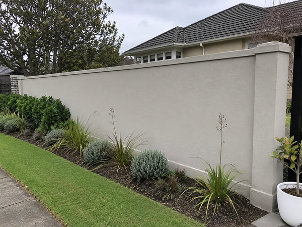 Lightly textured rendered garden wall beside simple Canterbury planting