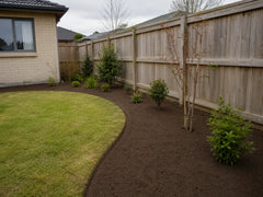 Fresh screened topsoil spread through a planted garden bed beside a Canterbury home